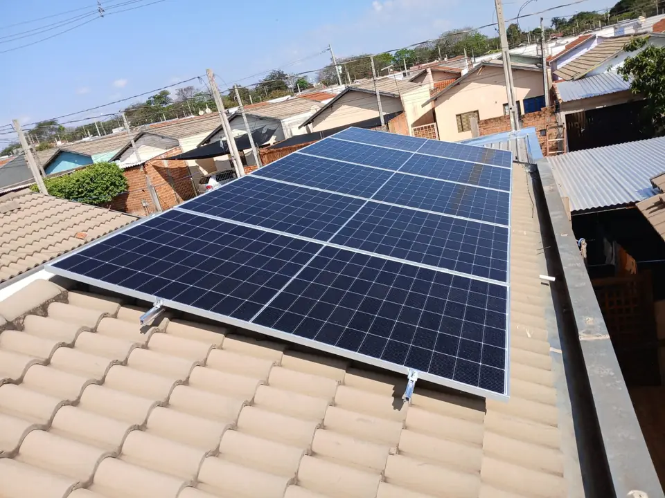 Painéis solares em telhado residencial em bairro urbano, com céu azul