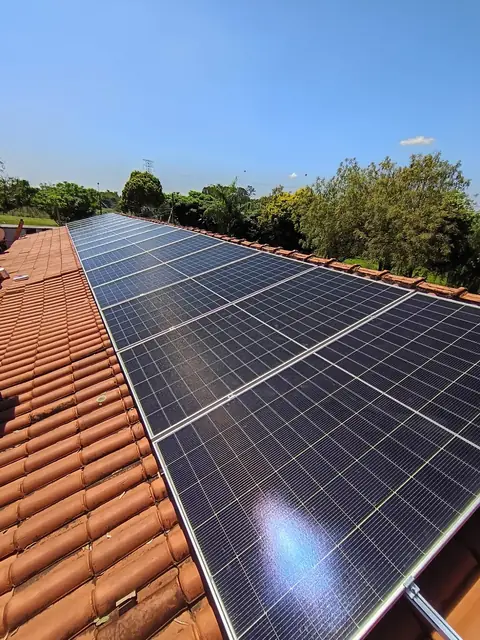 Painéis solares em telhado cerâmico com árvores ao fundo
